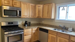 Cucina con mobili in legno, elettrodomestici in acciaio inossidabile, piani di lavoro in granito e una finestra con vista.