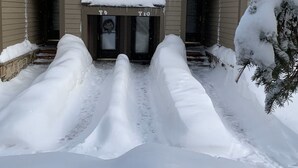 Una casa de dos pisos amb un teulat cobert de neu i estalactites penjant de les impostes.