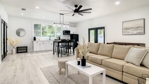 A modern living room with a sofa, coffee table, and dining area. - Cozy Getaway Home Near Siesta Key Beach  (Sarasota)