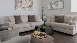 A modern living room with a grey sofa set, a coffee table, and a ceiling fan. - 🏈 GAME DAY WATCH PARTY!  (Bryan)