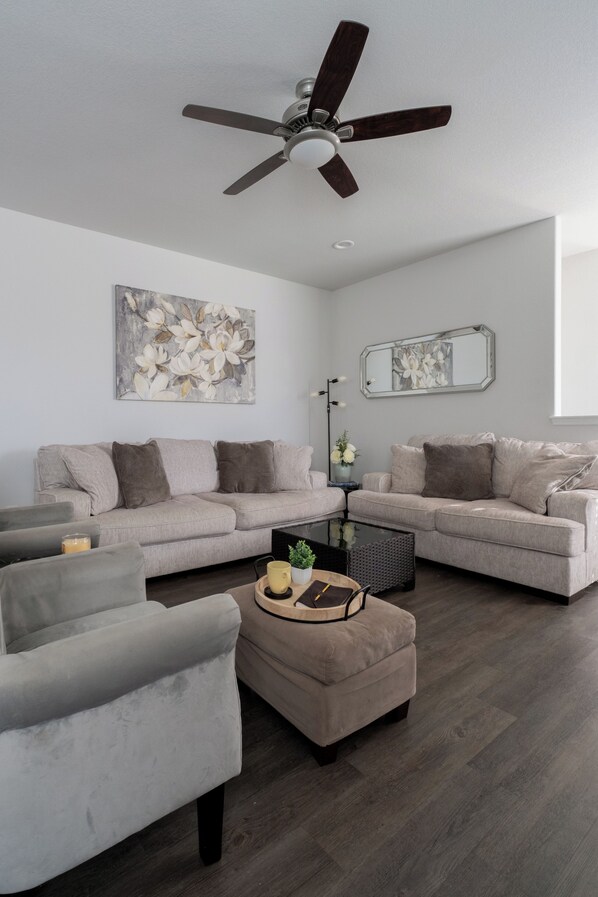 A modern living room with a grey sofa set, a coffee table, and a ceiling fan.