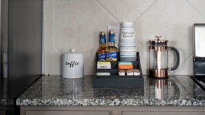 A kitchen with grey cabinets, a coffee maker, and a coffee dispenser on the counter. - 🏈 GAME DAY WATCH PARTY!  (Bryan)