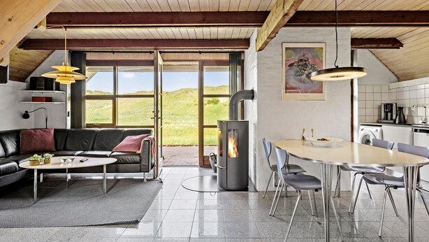 A modern loft with a large open-plan living and dining area, a fireplace, and a view of the outdoors. - Cozy home in Harboøre with WiFi (Harboøre)