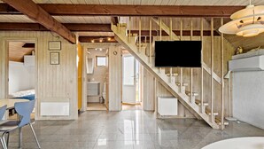 A modern interior with a wooden staircase, a flat-screen TV, and a dining area with chairs. - Cozy home in Harboøre with WiFi (Harboøre)