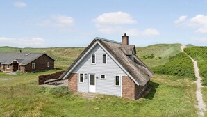 A traditional house with a steeply pitched roof, a brick foundation, and a thatched roof extension. - Cozy home in Harboøre with WiFi (Harboøre)