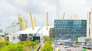 Un paysage urbain avec des bâtiments modernes, des grues de construction et un parking.