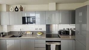 Une cuisine moderne avec des armoires grises, un évier en acier inoxydable, un four encastré et une fenêtre au-dessus du plan de travail.