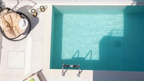 A rooftop pool with clear blue water, a sun lounger, and a small table with a hat and sunglasses. - Pomaria Boutique Residences (Lefkada)