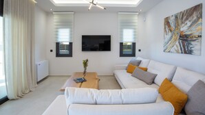 A modern living room with a sofa, coffee table, and artwork on the wall. - Pomaria Boutique Residences (Lefkada)
