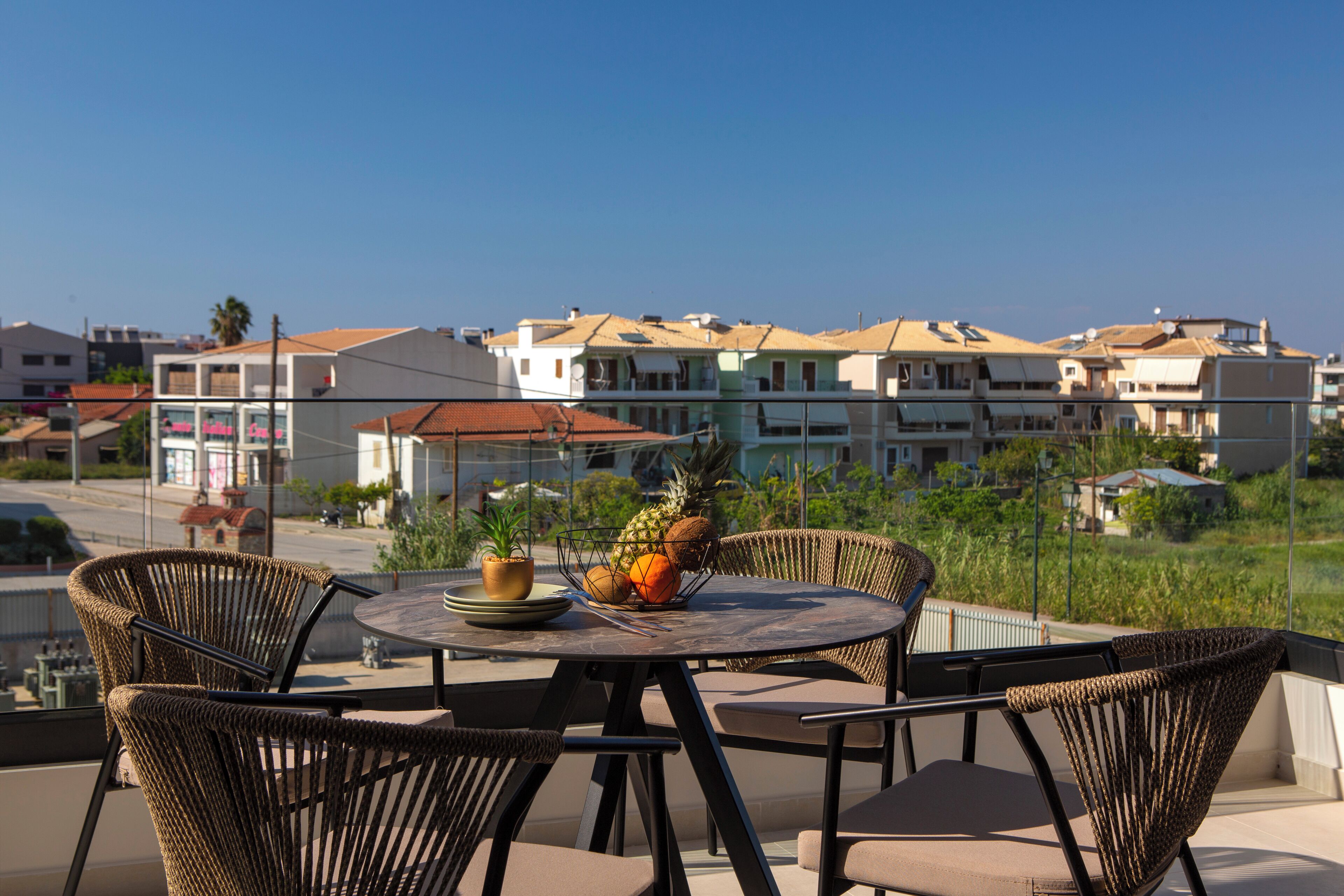 A balcony with wicker chairs, a round table, and a fruit bowl.
