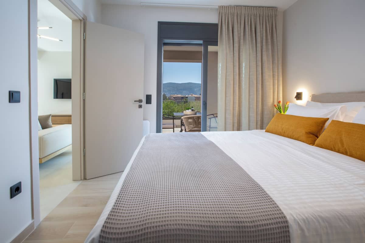 Ein Hotelzimmer mit Bett, Blick ins Freie, einem Balkon und einem an der Wand befestigten Fernseher.