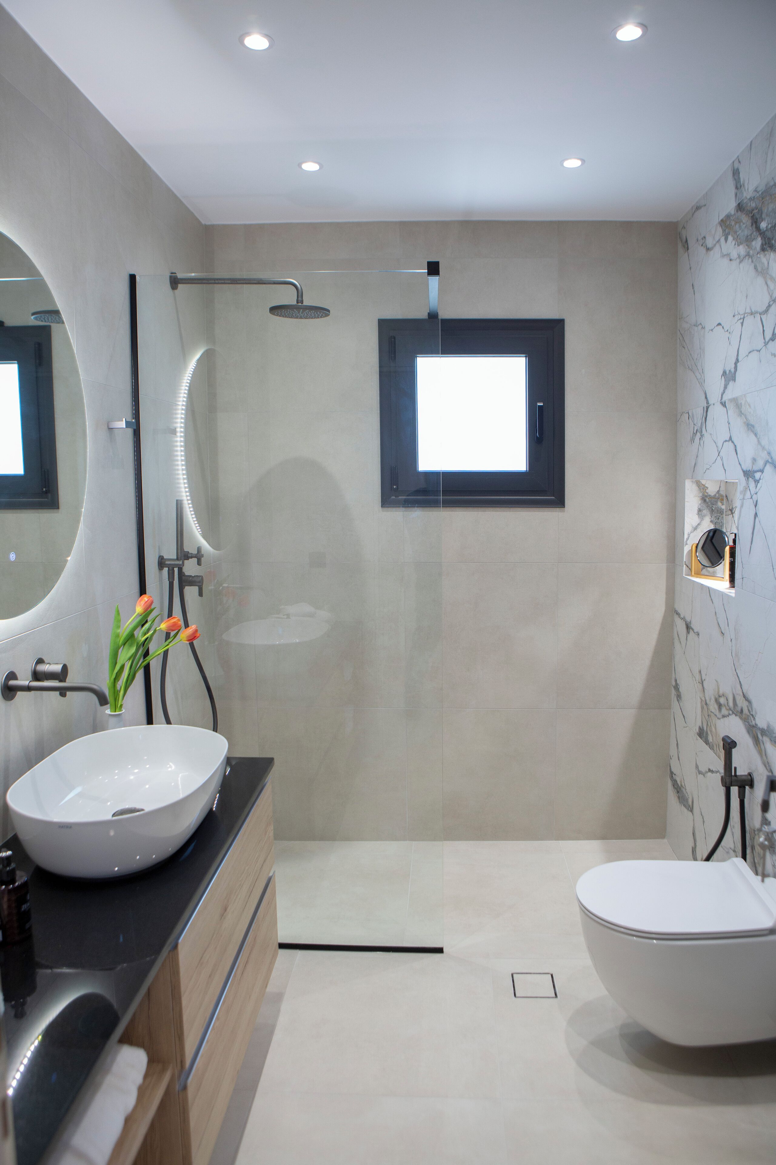 Une salle de bain moderne dotée d’un grand lavabo, de toilettes séparées et d’une douche à l’italienne.