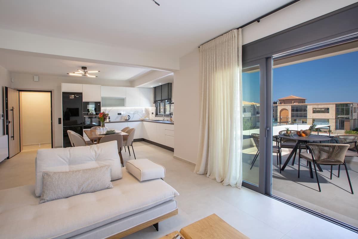 Eine moderne Wohnung mit Wohnbereich, Essplatz und einem Balkon mit Blick auf die Stadt.