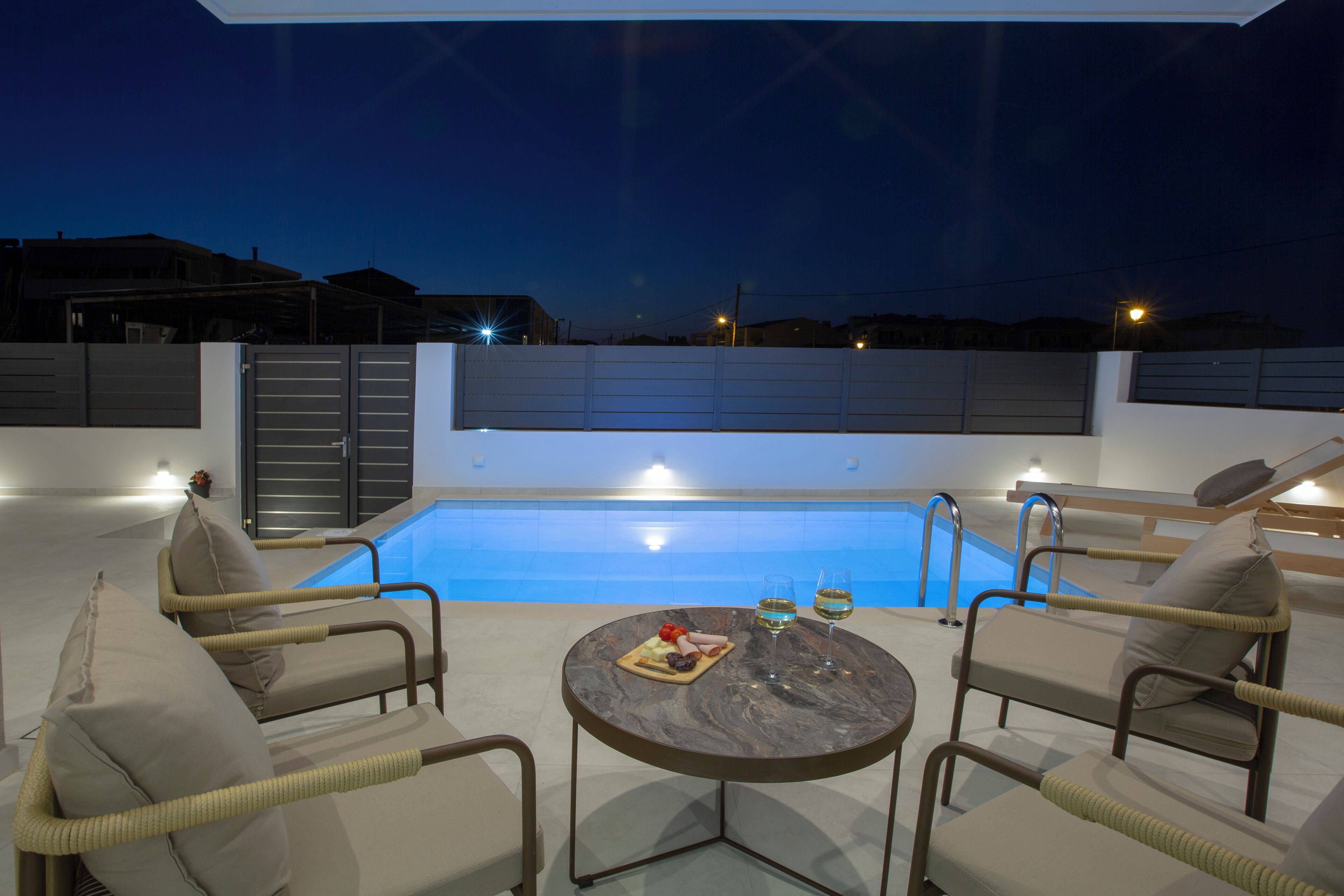 A rooftop pool area with lounge chairs, a table with food and drinks, and a clear view of the pool.