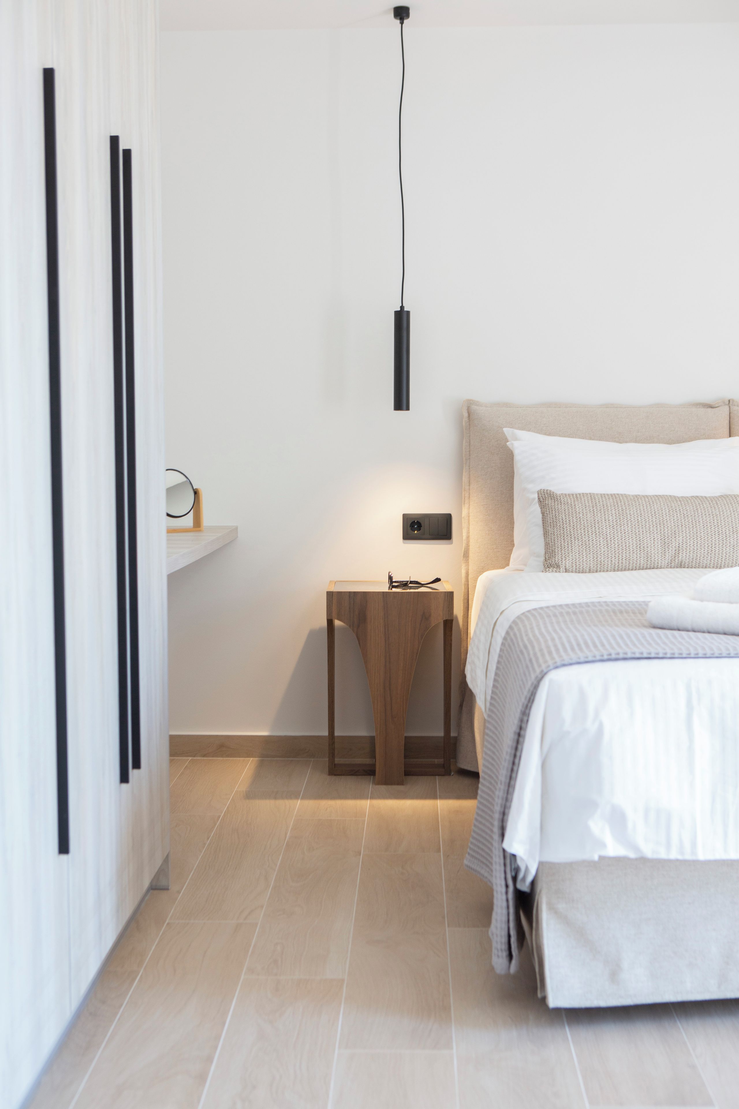 Un dormitorio moderno con cama, mesita de noche y lámpara de pared.