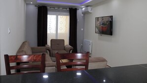 A conference room with a black table, two wooden chairs, a sofa, and a radiator.