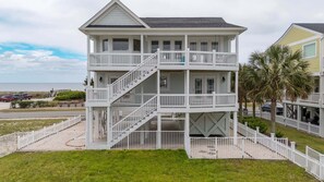 A multi-story beachfront house with a balcony, a staircase, and a white fence. - Relax  in "3 Bouys & A Pearl," beautiful 4 bedroom island home with a community pool. (Holden Beach)