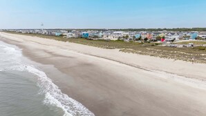 Un quartier résidentiel situé au bord de la plage, avec des maisons, un phare et une route.