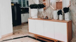 Eine moderne Küche mit weißen Schränken, einem schwarzen Kühlschrank und einer Wand mit geometrischem Muster.