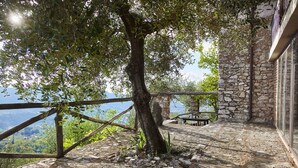 Un bâtiment en pierre doté d’un balcon donnant sur un paysage montagneux.