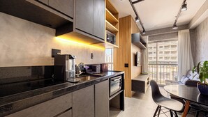 A modern kitchen with a built-in oven, a sink, and a dining area with a table and chairs. - NOV - NEXT ONE Vila Nova Conceição (São Paulo)