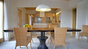 A dining area with a wooden table, wicker chairs, a central black pedestal, and a hanging light fixture. - Country House 'Son Puca 1' with Private Pool, Wi-Fi and Air Conditioning (Illes Balears)