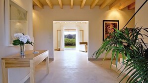 A hallway with a wooden ceiling, a desk with a vase of flowers, a large plant, and a framed picture on the wall. - Country House 'Son Puca 1' with Private Pool, Wi-Fi and Air Conditioning (Illes Balears)