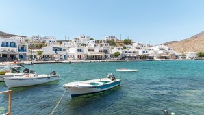 Un pueblo costero con edificios blancos, barcos y un cielo azul despejado.