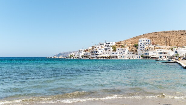 Un pueblo costero con edificios blancos, una playa y barcos.