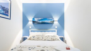 A bedroom with a bed, pillows, and a wall-mounted picture. - Apartment 'Sea View on the Beach' with Sea View, Shared Pool and Wi-Fi (Douarnenez)