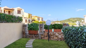 A residential area with stone walls, a pathway, and a well-maintained lawn.