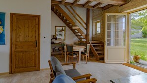A wooden-framed room with a staircase, a dining area, and a view of the outdoors.