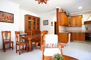A dining area with a wooden table and chairs, a cabinet with glass doors, and a kitchen with wooden cabinets.