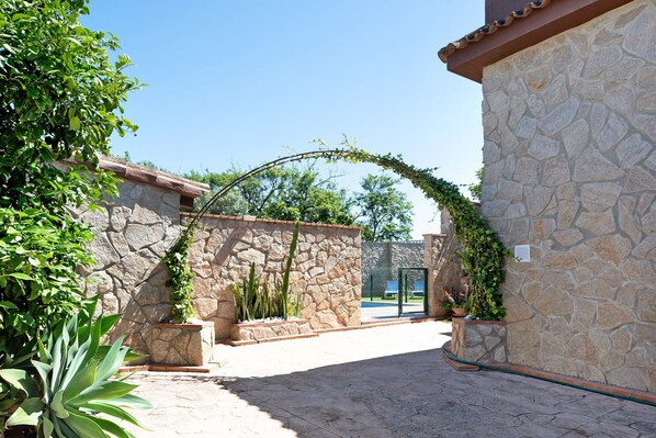 A stone building with a curved archway, potted plants, and a clear blue sky.