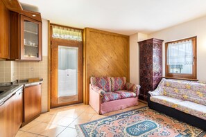 Une cuisine avec des meubles en bois, un canapé rose, un tapis à motifs et un buffet en bois aux motifs complexes.