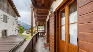 Ein hölzerner Balkon mit Blick auf einen Berg, eine Holztür und ein Geländer aus Holz.