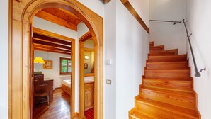 A wooden staircase with a handrail and a door leading to a room with a bed and a window. - Apartment 'Casa San Giovanni 2 A Vinigo' with Mountain View, Balcony and Wi-Fi (Vinigo)