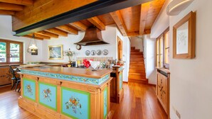 A kitchen with wooden beams, a central island, and a staircase leading to another level. - Apartment 'Casa San Giovanni 2 A Vinigo' with Mountain View, Balcony and Wi-Fi (Vinigo)