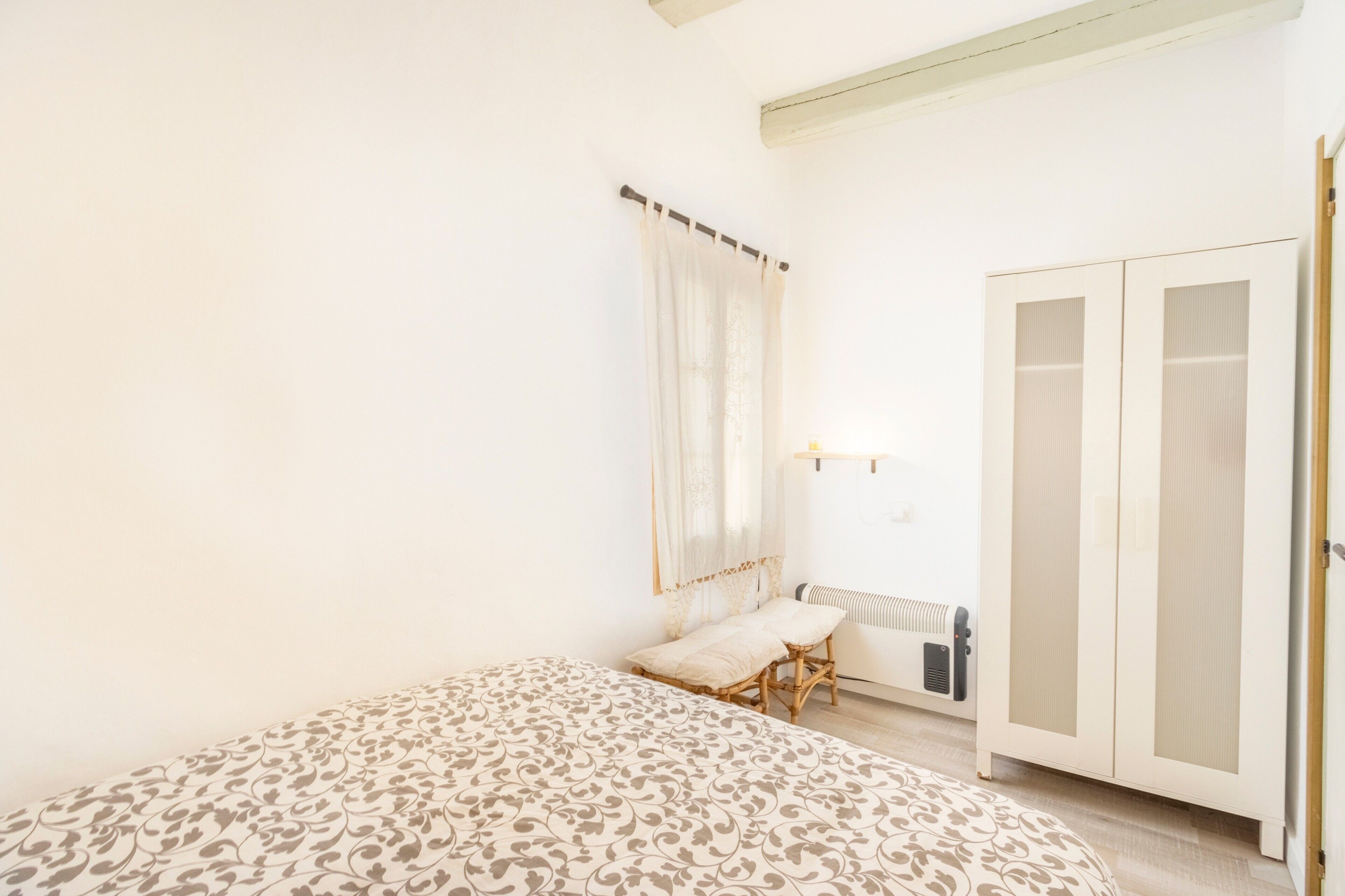A bedroom with a bed, a bedside table, a wardrobe, and a radiator.