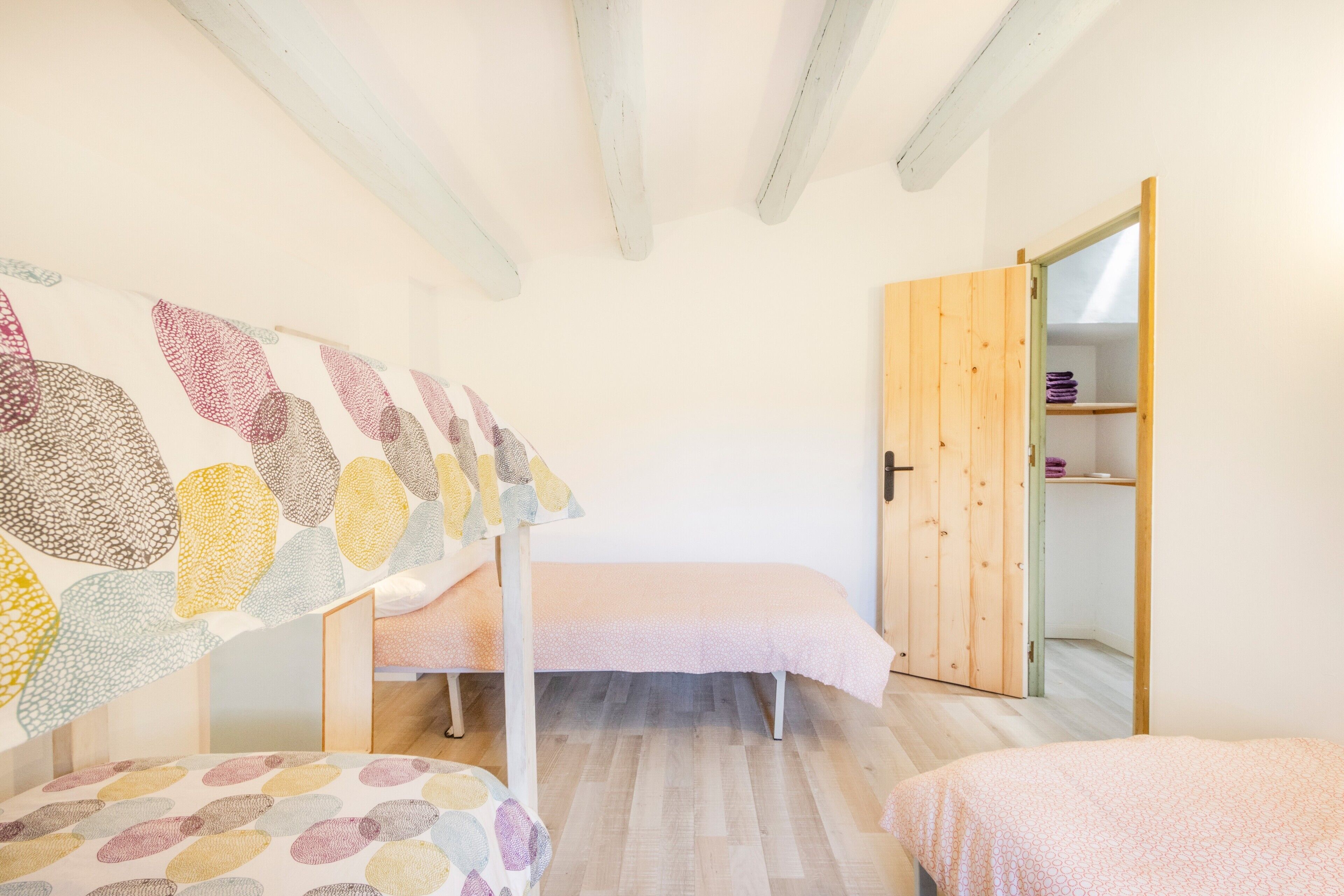 Una camera da letto con una cuccetta, un letto singolo, un'armadietto in legno e una parete con opere d'arte astratte.