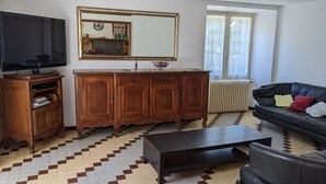 Sala de estar com televisão, armário de madeira, sofá e piso estampado.
