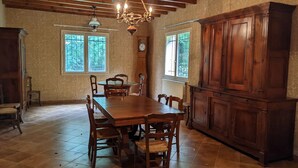 Uma sala de jantar com uma mesa e cadeiras de madeira, um candelabro e um armário de madeira grande.