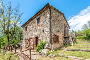 A stone building with a wooden staircase leading to a door, surrounded by trees and a clear sky. - Farmhouse 'Casa Stella' with Infinity salt water pool shared, Private Terrace and Wi-Fi (Chiusdino)