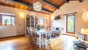 A dining area with a wooden table and chairs, a bookshelf, and a sofa with a view to the outdoors. - Farmhouse 'Casa Stella' with Infinity salt water pool shared, Private Terrace and Wi-Fi (Chiusdino)