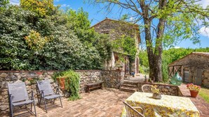 An outdoor patio with stone walls, a table with a floral tablecloth, and chairs. - Farmhouse 'Casa Stella' with Infinity salt water pool shared, Private Terrace and Wi-Fi (Chiusdino)