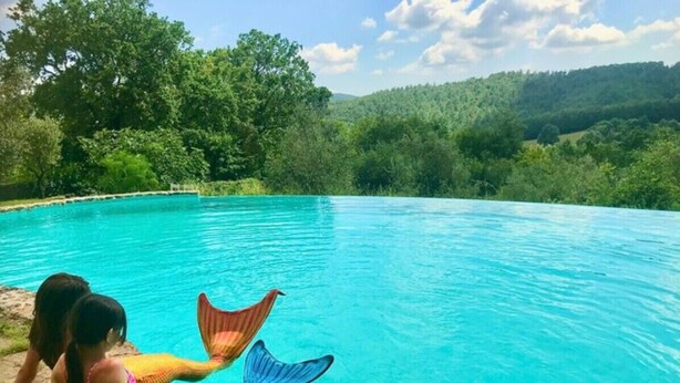 A swimming pool with clear blue water, surrounded by lush greenery and trees. - Farmhouse 'Casa Stella' with Infinity salt water pool shared, Private Terrace and Wi-Fi (Chiusdino)