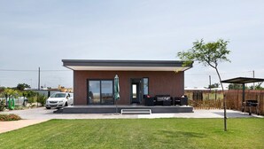 A modern building with a car parked in front, a small lawn, and a wooden fence. - Holiday Home 'Casa Valle' with Private Pool, Wi-Fi and Air Conditioning (Conil de la Frontera)