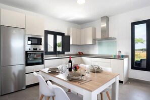 Una cocina moderna con armarios blancos, horno empotrado, microondas y campana extractora de acero inoxidable.