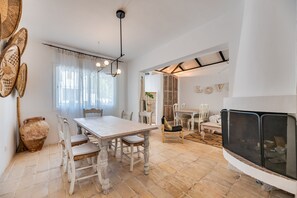 Un comedor con una mesa y sillas blancas, un jarrón grande y una chimenea.