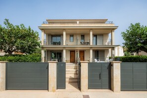 A two-story residential building with a balcony, a gated entrance, and a staircase leading to the entrance. - Holiday Home 'Casa Juan' with Sea View, Wi-Fi and Air Conditioning (Can Picafort)
